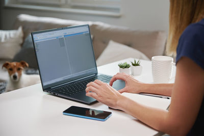 Woman working remotely from home office, using laptop