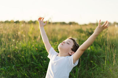 Boy closed her eyes and praying in a field at sunset