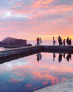 People on beach against sky during sunset