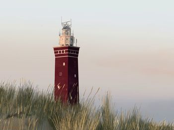 Lighthouse by sea against sky