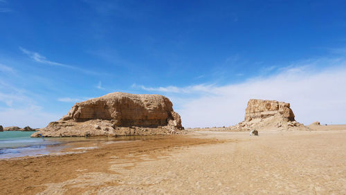 Rock formations on beach against sky