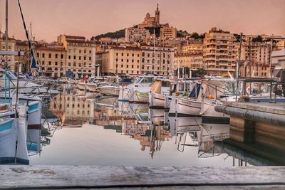 Boats moored in harbor against buildings in city