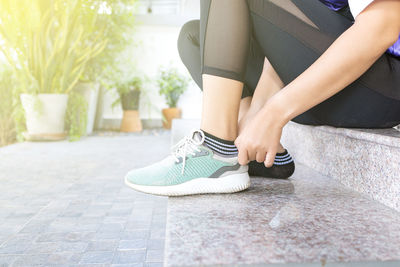 Low section of woman sitting on footpath
