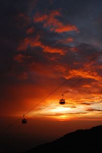 Silhouette of overhead cable car against sky during sunset