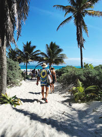 Rear view of women walking on palm trees