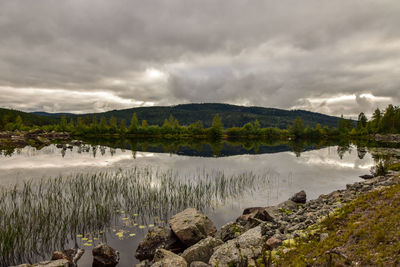 Scenic view of lake by mountains against sky