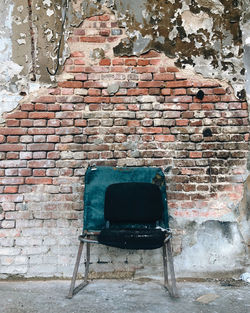 Empty chair against brick wall