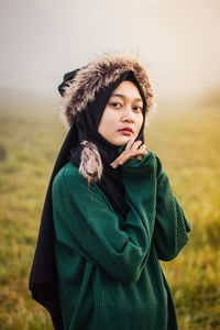 Portrait of woman in warm clothing standing on field