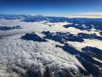 Aerial view of snowcapped mountain against blue sky