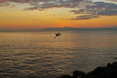 Silhouette person in sea against sky during sunset