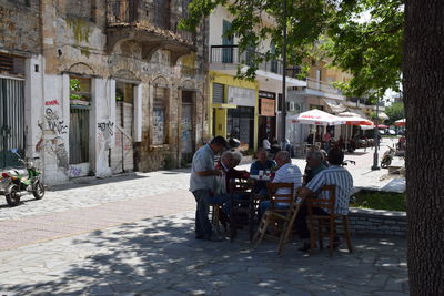 Men sitting on footpath in city