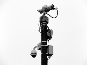 Low angle view of security camera on pole against clear sky