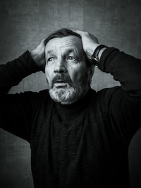 Worried senior man with hands in hair looking away against wall