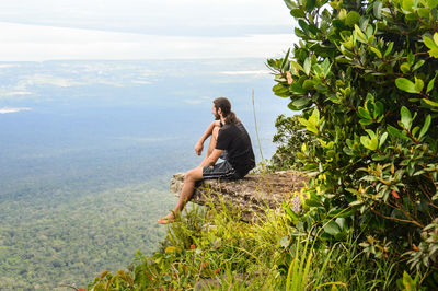 Hiker sitting on cliff during foggy weather