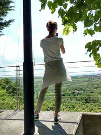 Rear view of woman standing against trees