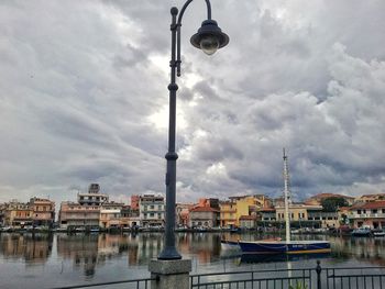 Buildings by river against sky in city