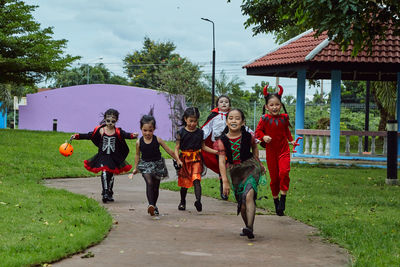 Girls in costumes running on footpath during halloween