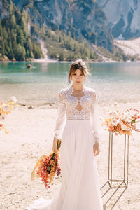 Full length of woman standing by sea against mountains