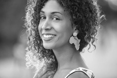 Close-up portrait of smiling young woman with curly hair