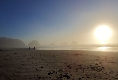 Scenic view of beach against clear sky during sunset