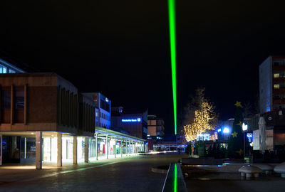 Illuminated street amidst buildings in city at night