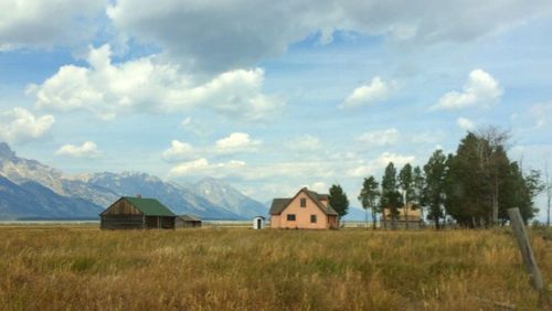 Houses on field against cloudy sky