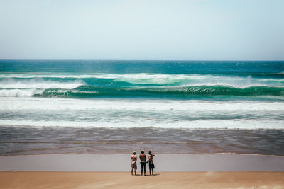 People at beach against clear sky