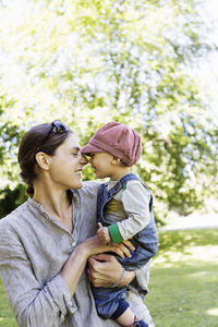 Happy mother and baby girl rubbing noses at park