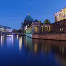 Illuminated bridge by berlin cathedral over river at dusk