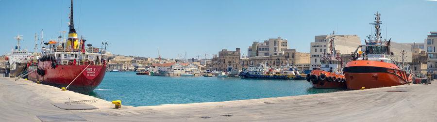 Sailboats in harbor against clear sky