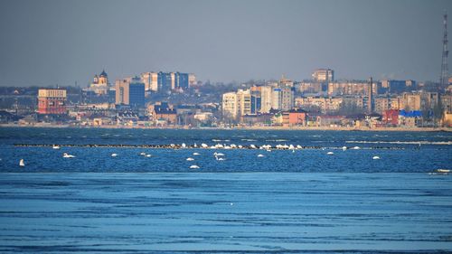 Sea by buildings against sky in city