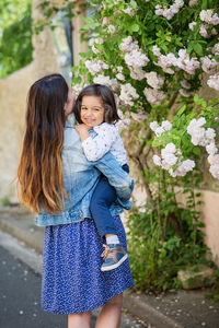 Mother and little handsome baby boy looking at bush with white roses