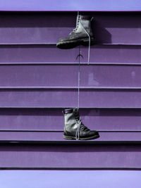 Abandoned shoes hanging on purple metal