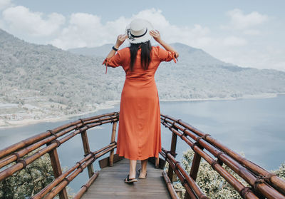 Full length of woman standing on railing against mountain