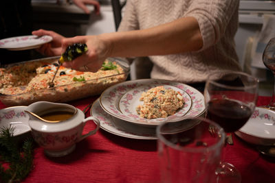 Midsection of woman having food served on table during a festive meal