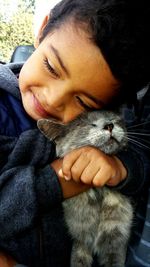 Close-up of young boy hugging cat