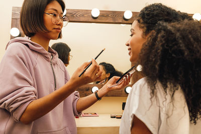 Beautician applying make-up to young woman