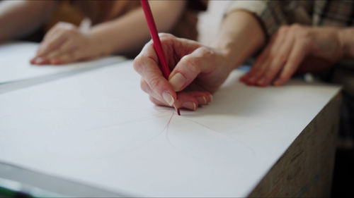 Midsection of teacher teaching drawing to kid