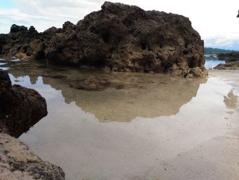 Rock formations by sea against sky