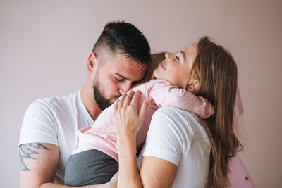 Happy family father young man and mother with baby girl little daughter having fun in room at home