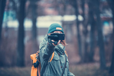 Mid adult woman photographing while standing in forest