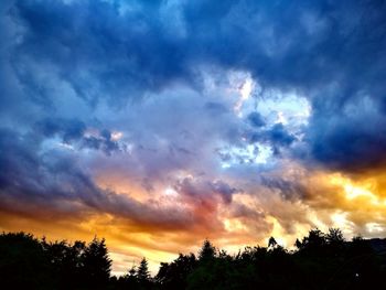 Low angle view of silhouette trees against dramatic sky