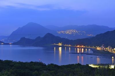 Scenic view of lake by mountains against sky at night