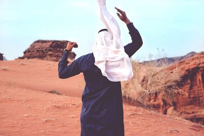 Rear view of man walking in desert against sky