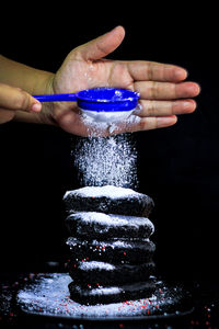 Close-up of hand holding stack against black background