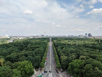 Aerial view of trees in city against cloudy sky