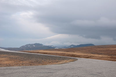 Road leading towards mountains against sky