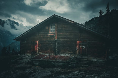 Abandoned building in snow covered houses against sky