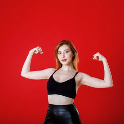 Portrait of a smiling young woman against red background