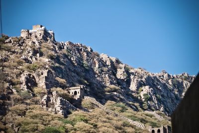 Low angle view of castle on mountain against blue sky